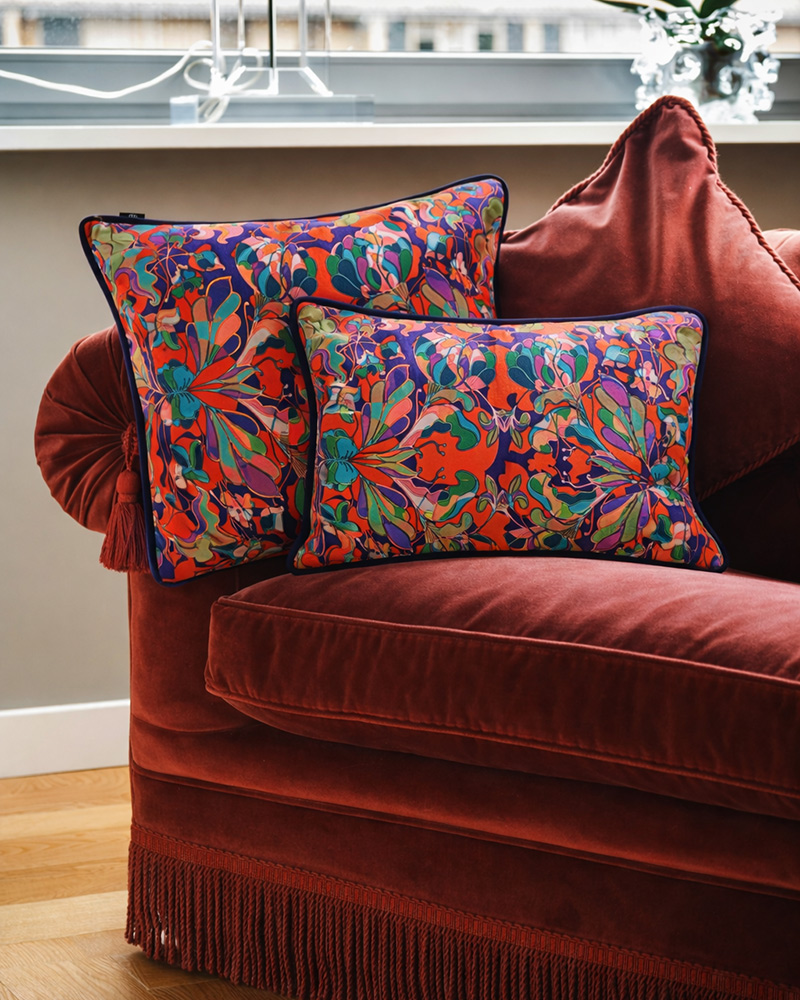 Coussins en velours rouge et motif floral imprimé Au Jardin sur un fauteuil